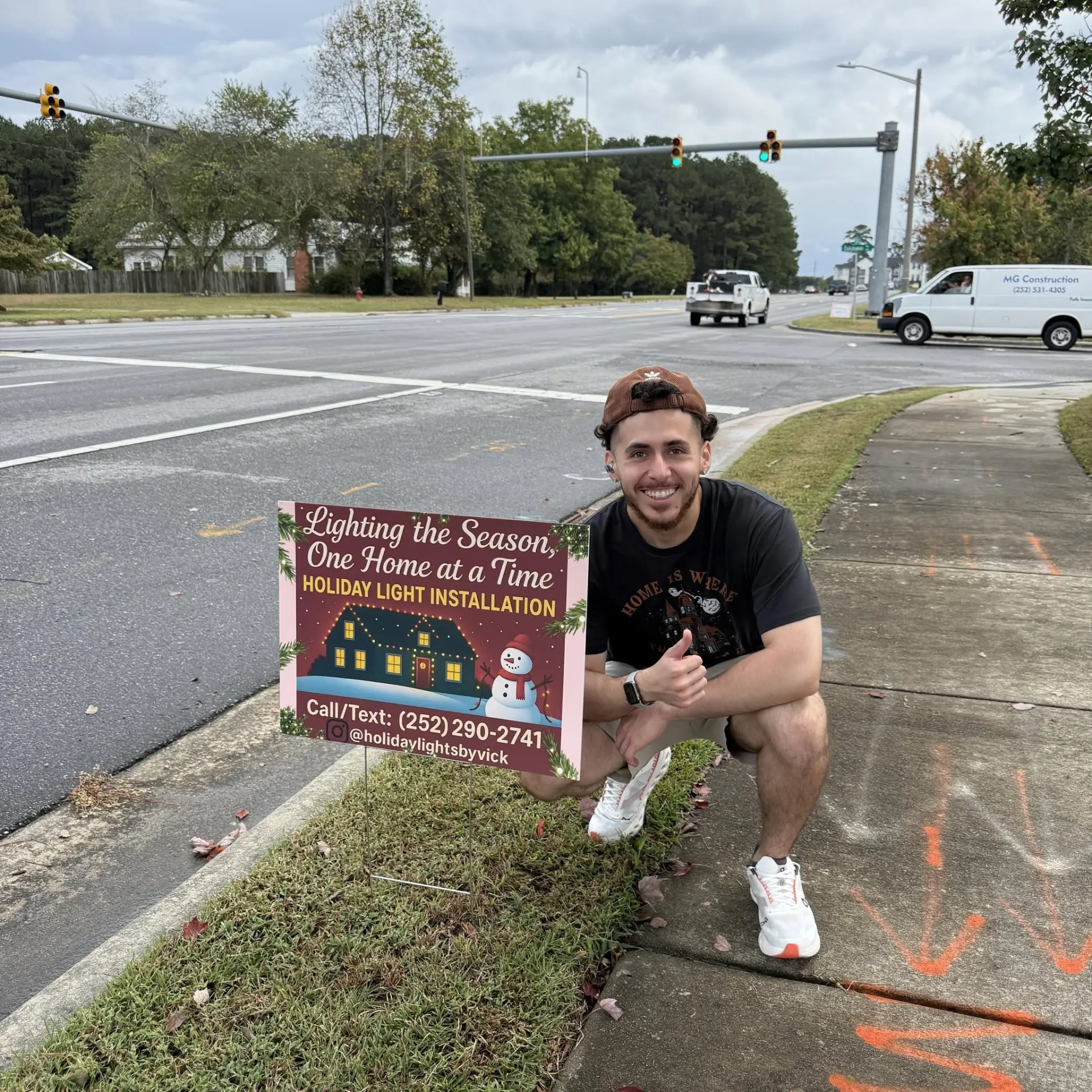 VICK crouching beside the Holiday Lights by VICK yard sign